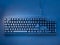 PC keyboard covered with snow illuminated by blue neon light with inscription merry christmas