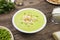 Pea soup `Saint-Germain` in a white bowl on an old rustic wooden table. Selected focus.