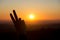 A peace hand gesture silhouetted by the sunset over Dartmoor, UK