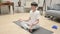 Peaceful Asian Man Meditating on Yoga Mat at Home