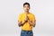 Peaceful attractive asian young man in yellow t-shirt with tattoos, hold hands in pray, palms together over chest, look