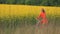 Peaceful attractive blonde lady in red dress is happily riding the bike along the blooming field covered with yellow