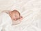 Peaceful baby lying on a bed while sleeping in a bright room