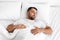 Peaceful calm tired millennial caucasian muscular man lies on white comfortable bed, soft pillow, sleeps alone