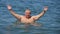 Peaceful carefree older man with outstretched arms. Man splashing water during summer holidays.