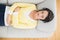 Peaceful casual brunette in yellow cardigan listening to music with headphones