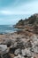 Peaceful coastal landscape featuring a rocky beach with a house on a hill