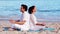 Peaceful couple meditating in lotus pose at the beach