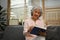 Peaceful elderly woman relaxing on comfortable sofa in living room and reading book