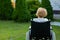 Peaceful elderly woman sitting in a wheelchair on a walk outdoors.