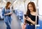 Peaceful ethnic female leaning on handrail and messaging on mobile phone while riding modern train, Concept for city life of