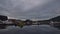 Peaceful harbor of TromsÃ¸ with docking boats and landing stage reflected in the calm water and road bridge TromsÃ¸brua.