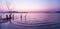 A peaceful lakeside at sunset, beautiful gently waves and leafless tree trunks. Mountains, lighting and twilight sky blurred