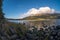 Peaceful landscape of a lake, clouds formation, hill and blue sky