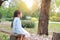 Peaceful little girl sitting on wood log in the summer garden with looking out