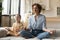 Peaceful mother with little daughter meditating on couch together