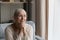 Peaceful older woman sits on couch, smile staring out window