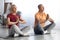 Peaceful pensioners sitting on fitness mat in lotus pose