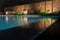 Peaceful pool reflections looking toward mood lighting and lush