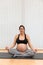 A peaceful pregnant woman sitting on a mat doing yoga with eyes closed in a health center with copy space