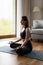 Peaceful pretty yogi woman in sportswear practicing meditation at home