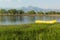 Peaceful river flow and a yellow fishing boat on the grassy shore