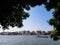 Peaceful scene of local traditional long tail boat sailing on Chao Phraya river with riverside buildings skyline and blue sky