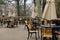 Peaceful scene of tables and chairs with tied umbrellas on outdoor restaurant patio