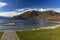 Peaceful scenic view small jetty in European village dock on idyllic calm lake waters surface surrounded by Alps mountain snowy