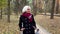 Peaceful senior woman with gray hair stands in forest, admires nature. Beautiful elderly female model in black coat