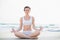 Peaceful slim brown haired model in white sportswear meditating in lotus position