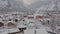 Peaceful small town under deep fresh snow on a sunny frosty winter day. Cinematic aerial view of a mountain village in a