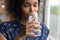 Peaceful smiling young African American woman drinking pure filtered water