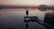 Peaceful sunset over the water. Someon on pier in yellow raincoat watching