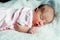 Peaceful sweet newborn infant baby lying on bed while sleeping in a bright room