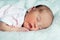 Peaceful sweet newborn infant baby lying on bed while sleeping in a bright room