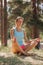 peaceful woman meditates in forest among trees in lotus position. breathing and physical practice
