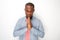 Peaceful young black man praying with hands clasp together by white wall