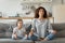 Peaceful young mother and little daughter meditating, doing yoga exercise