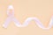 Peach color ribbon curl on pastel orange or beige color background with copy space, symbol for Uterine and Endometrial cancer