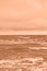 Peach fuzz toned sea beach. North sea. Stormy weather: strong waves, gloomy sky, sea foam. Trendy colour 2024.