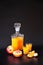 Peach liqueur in a transparent glass bottle and two glasses, next to it are pieces of ripe fruit on a black background