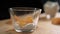 Peach slices falling into glass cup with yogurt above wooden surface