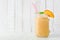Peach smoothie in a mason jar glass, side view with a white wood background