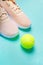 Peach sneakers with tennis ball on green background. Concept of healthy lifestile, everyday training.