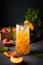 Peach tea with ice and rosemary on a tall glass. Vegan homemade healthy drink on a dark background with fresh fruits