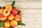 Peaches in a basket on a wooden background with a slice of sliced juicy peach with a stone