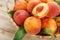 Peaches in a basket on a wooden background with a slice of sliced juicy peach with a stone