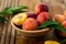 Peaches with leaves in a wooden bowl with peach in halves on top. Flat lay composition with ripe juicy peaches. Harvest of peaches