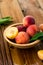 Peaches with leaves in a wooden bowl with peach in halves on top. Flat lay composition with ripe juicy peaches. Harvest of peaches